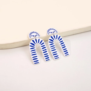 Detail of U-shaped acrylic earrings with blue porcelain patterns on white surface