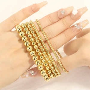 Detailed close-up of five 18K gold-plated beaded stretch bracelets for layering