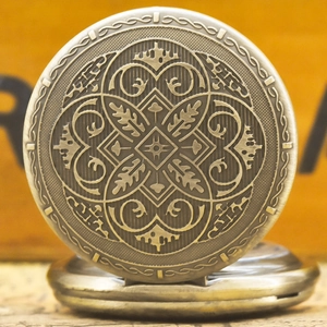 Macro detail of antique bronze pocket watch cover with intricate vintage floral engravings