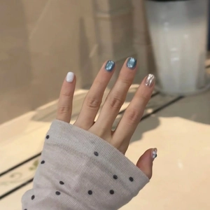 Blue cat-eye and daisy press-on nails with metallic silver accents on short round shapes