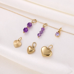 Detailed view of vintage gold heart pendants and purple gemstone charms on white fabric