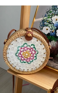 Detail of handcrafted rattan crossbody bag with colorful mosaic flower and leather strap