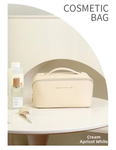 Detail of creamy apricot leather cosmetic bag with top handle and elegant gold zipper