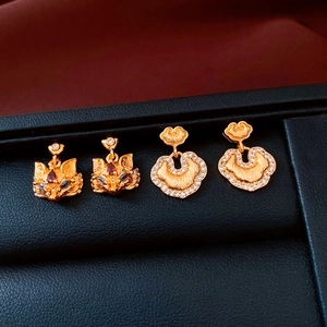 Detailed view of 24k gold plated fox and ruyi lock pendants with ruby and small diamonds