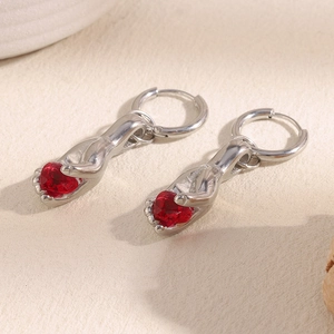 Detail view of silver earring featuring a hand holding a red heart crystal gemstone