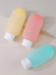 Close-up of pastel silicone travel bottles in yellow, pink and teal colors