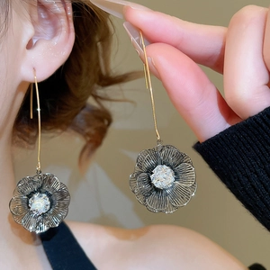 Gros plan détaillé de longues boucles d'oreilles fleur en or 18K avec un gros zircon