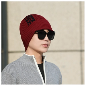 Detail of dark red ribbed knit beanie with black logo pattern and outdoor style