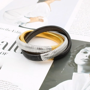 Close-up of three-layer 18K gold-plated elastic bangles in black, gold, and silver finishes