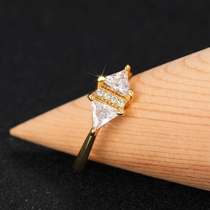 Macro view of gold triangle ring with sparkling zircon stones on a wooden stand