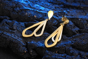 Detailed shot of gold titanium earrings with dual teardrop cutouts and matte texture