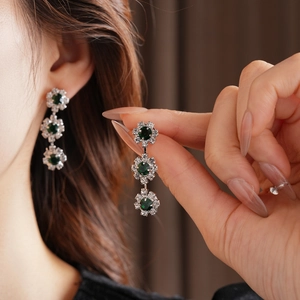 Detailed view of silver sunflower earrings with dark green stones and sparkling diamonds