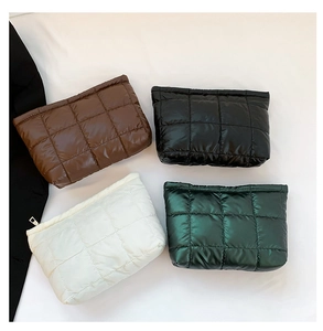 Detailed top view of quilted pouches in brown, black, cream and green with metal zippers
