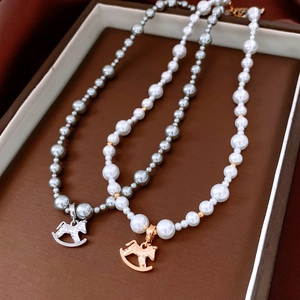 Detailed view of pearl necklaces with horse pendants in gold and silver on a tray