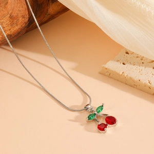 Close-up of a silver cherry pendant with red crystal gems and green leaf accents