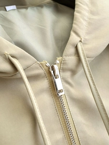 Detailed close-up of khaki jacket resin zipper and woven drawstring texture