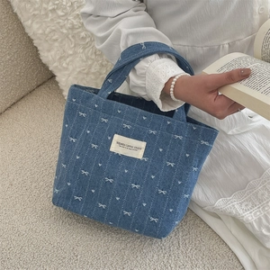 Detailed embroidery of white bows on a vintage blue denim handbag for daily commute