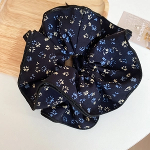Close-up of floral scrunchie in navy blue chiffon with delicate flower print texture