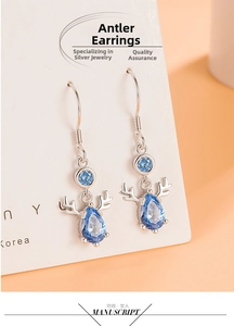 Detailed view of silver deer antler earrings with vibrant blue teardrop gemstones on a card