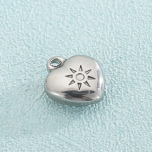 Silver heart pendant made of titanium steel with sun engraving on a blue surface