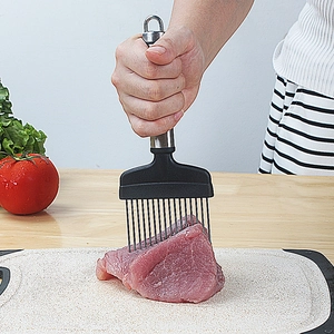 Manual stainless steel meat tenderizer tool with black handle used on raw meat