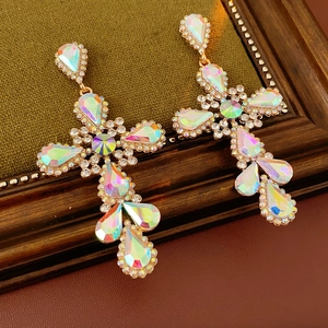 Detailed close-up of vintage gold cross earrings with colorful rhinestones on wood texture