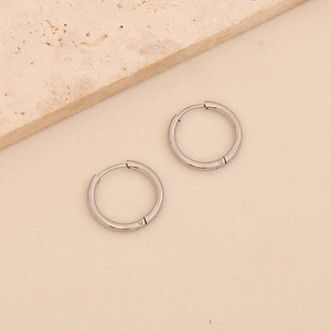 Polished silver titanium steel hoop earrings displayed on a minimalist stone background