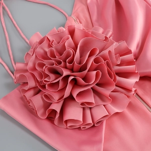 Détail de l'applique florale rose 3D et du tissu satiné sur une robe moulante
