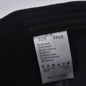 Detail of 100% cotton wash care label inside a black baseball cap with washing symbols