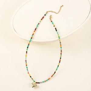 Macro detail of Bohemian beaded necklace with multi-color beads and gold heart pendant