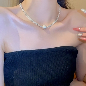 Dettaglio della collana d'argento multistrato con ciondolo di perla sulla clavicola