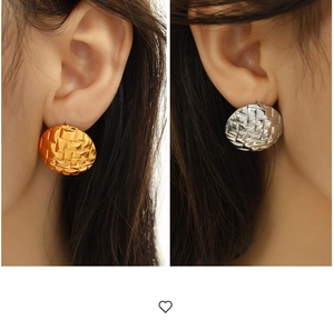 Close-up of gold and silver textured shell pattern round earrings worn on ears