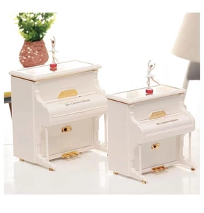 Close-up of white classical piano music boxes with rotating ballerina figures and glossy finish