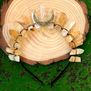 Detail of yellow crystal crown headband with moon charms on natural mossy wood