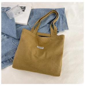 Detail of a brown corduroy tote bag with zipper and fashion label on denim fabric