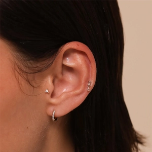 Close-up of S925 sterling silver star and triangle earrings worn on model's ear