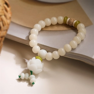 Handmade white bodhi seed bead bracelet with green accents and a carved lotus pendant