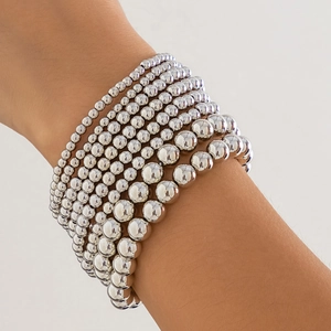 Close-up of stacked silver metal beaded bracelets with gradient size beads on a wrist