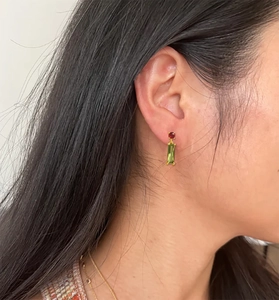 Detail of vintage star heart earrings with red and green gemstones worn by model