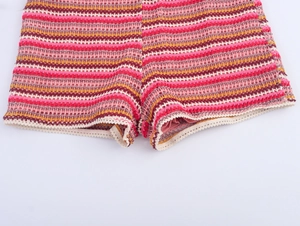 Macro detail of striped crochet knit shorts with wavy lace hem and multi-color texture