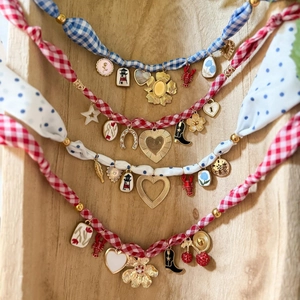 Collier en tissu floral avec des breloques vintage suspendu sur un fond en bois