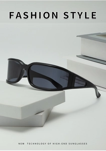Detail of Y2K black wrap-around sunglasses displayed on geometric stone and book props