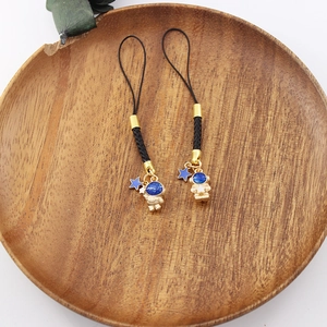 Detailed view of cute astronaut star phone charms with black braided strap and gold metal accents.
