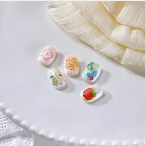 Dettaglio di adesivi per unghie in rilievo 3D con motivi floreali e frutti su un piatto