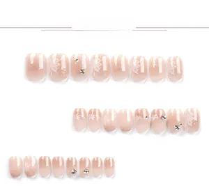 Detail of short square-oval press-on nails with nude pink gradient and floral motifs