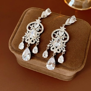 Close-up of sparkling zircon heart drop earrings on a brown velvet jewelry case