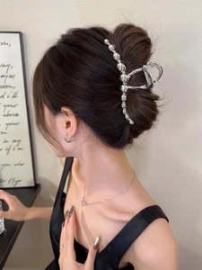 Silver metal hair claw clip with beaded chain design worn by a model in a side view
