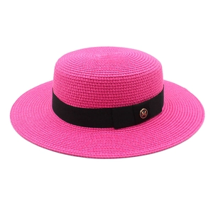 Détail du chapeau canotier rose avec ruban noir et logo métallique M doré élégant