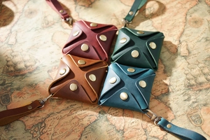 Four vintage square leather coin purses in wine, brown, and green on a retro map background