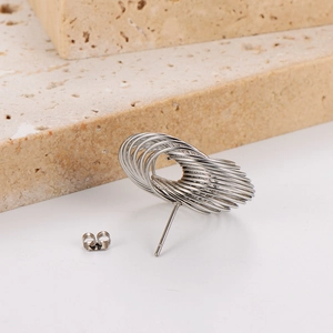 Detail of silver geometric multi-layer loop stud earring with back on beige stone